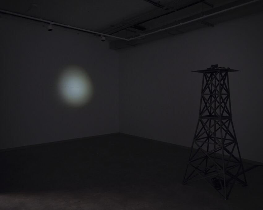 ciemna sala, na pierwszym planie widać wieżę, na drugim planie punktowe światło podświetlające tekst