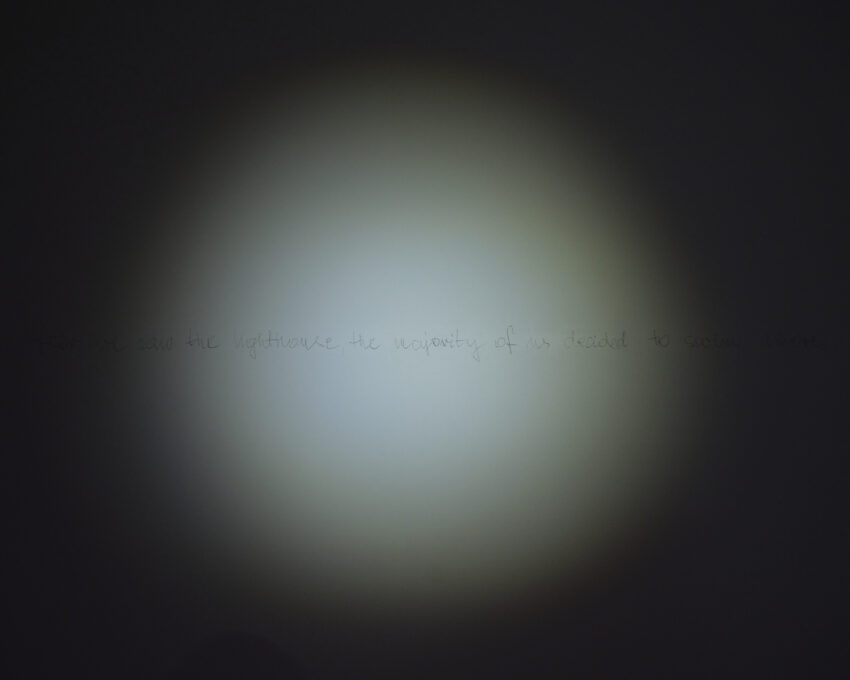 w ciemnej sali punktowe podświetlenie niewyraźnego tekstu zapisanego ołówkiem