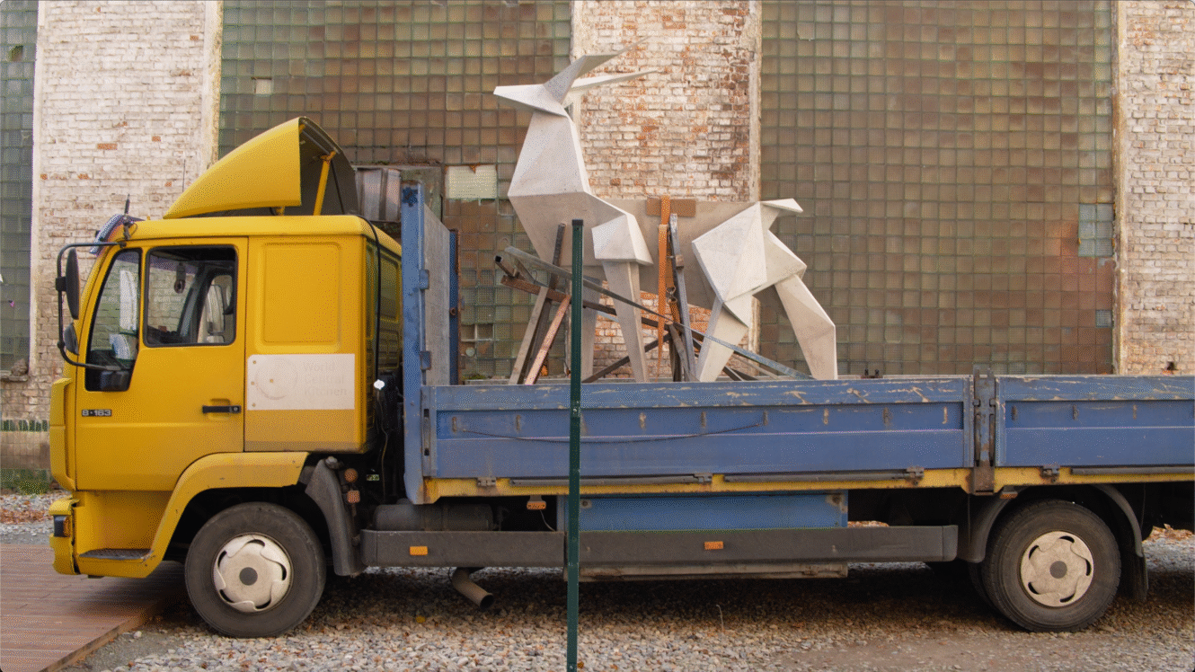 biała, geometryczna rzeźba jelenia na żółto-niebieskiej ciężarówce