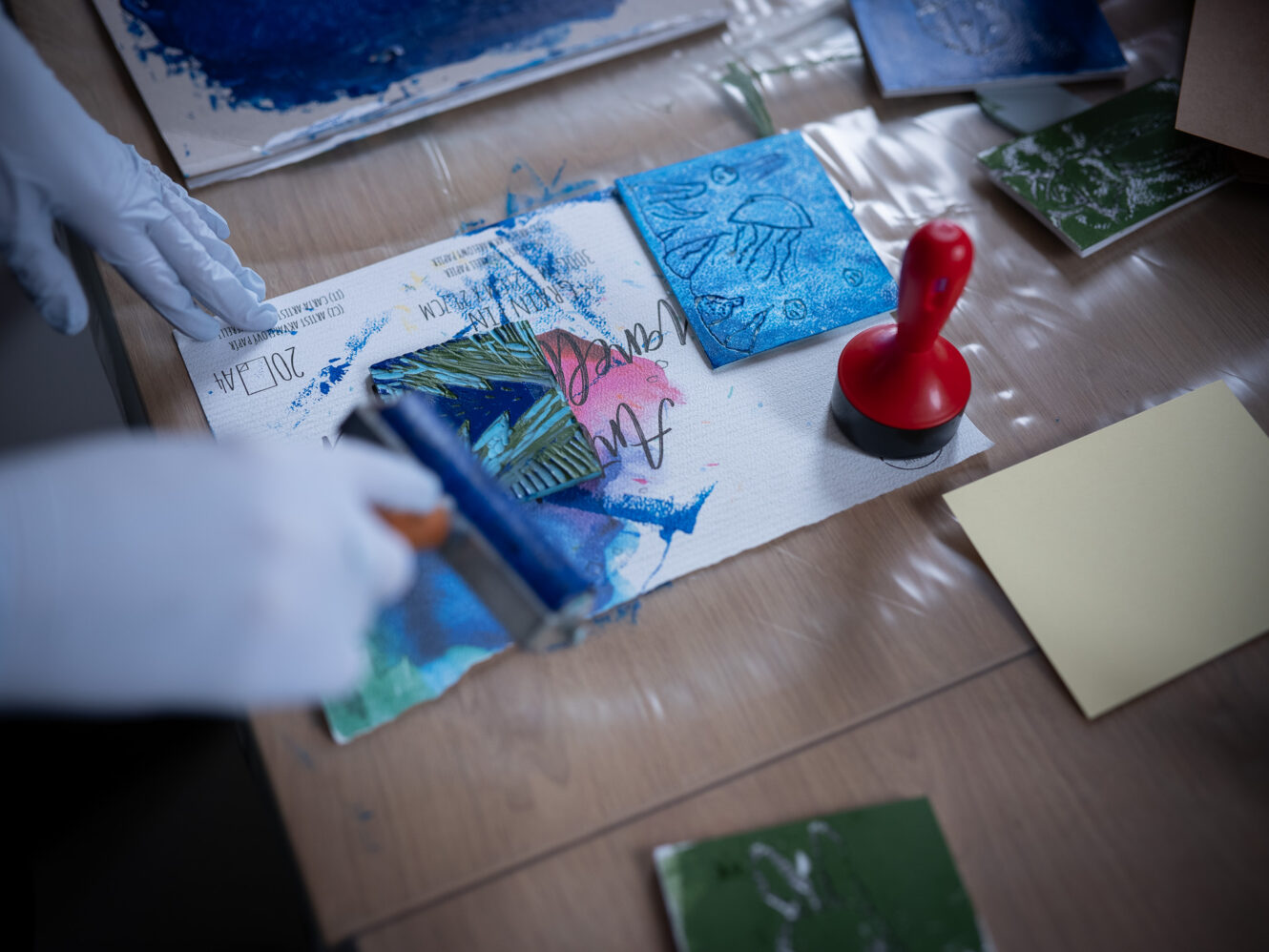 zdjęcie zrobione w trakcie warsztatów linorytu, nakładanie niebieskiej farby na gumową matrycę do odbijania